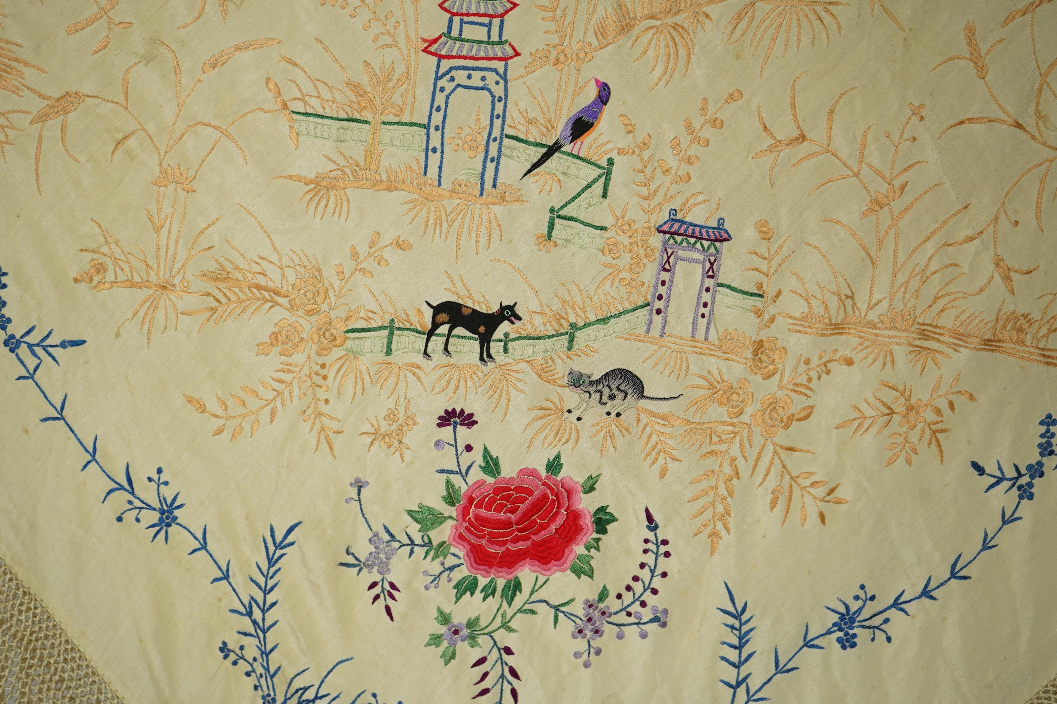 A Chinese cream silk polychrome embroidered shawl with a long fringe. Embroidered with four unusual corner cartouches of Pagoda, flowers, birds, cats and dogs. 132cm x 126cm.